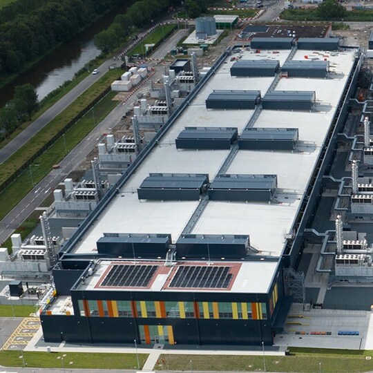 An aerial perspective of a massive, modern data center facility featuring a complex rooftop.