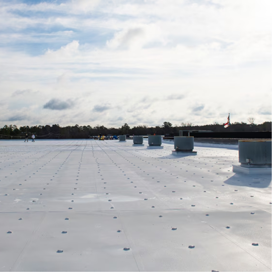A wide perspective of a clean, reflective white commercial roof under a clear sky.