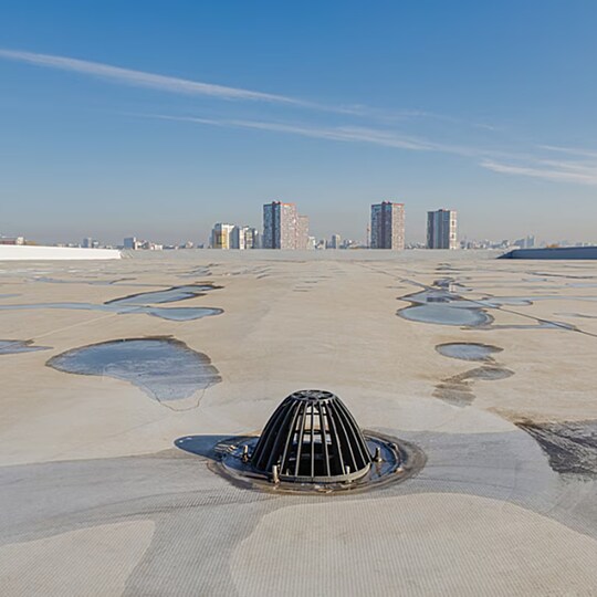 Commercial roof drain assembly on a white membrane roof designed for effective drainage and mitigating ponding water.