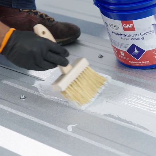 Up close shot of contractor applying GAF Acrylic Coatings to metal roof.