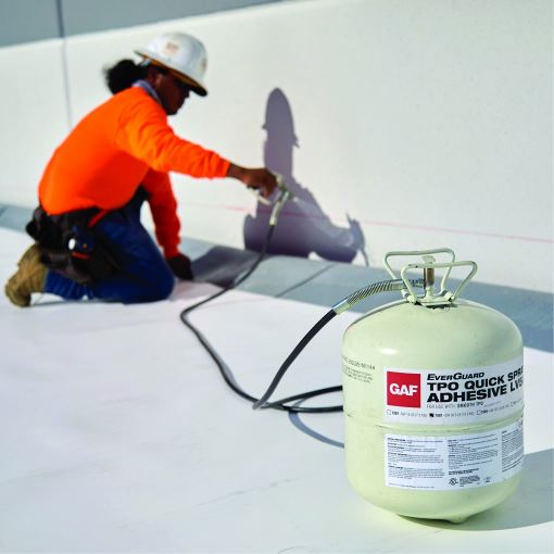 a roofer carrying a cannister of tpo quick spray adhesive
