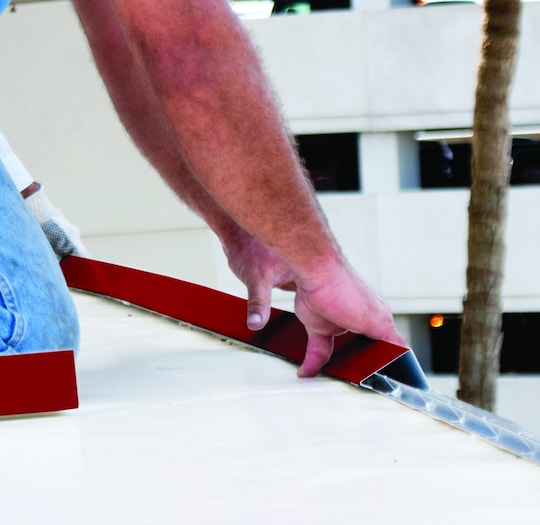 Roofer installing perimeter edge metal roofing products