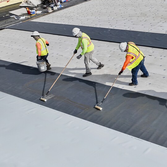 Contractors installing PVC roof membranes by GAF