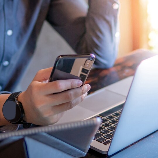 Person downloading commercial product data from laptop and phone
