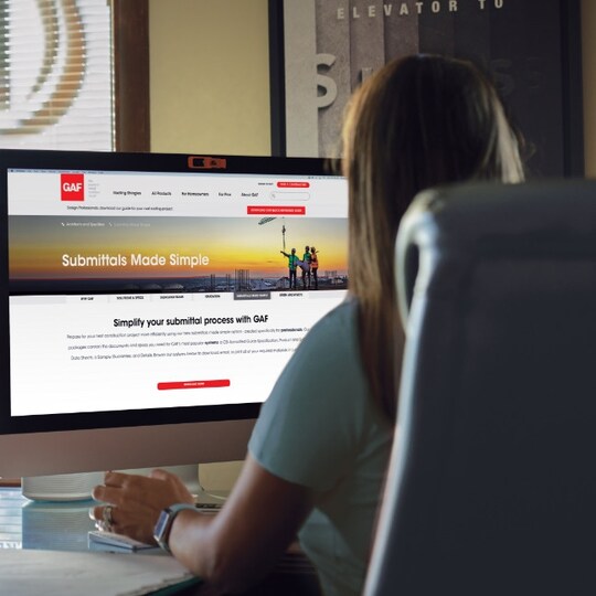 Women at computer downloading submittal pacakages from GAF website