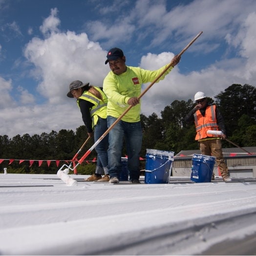 GAF contractors rolling coatings on a flat roof.