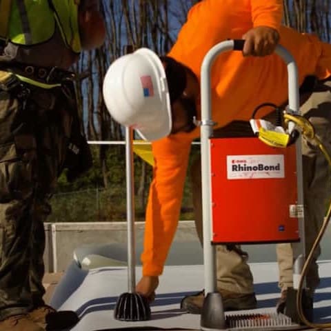 Contractors on commercial roof working on an induction welding roof installation
