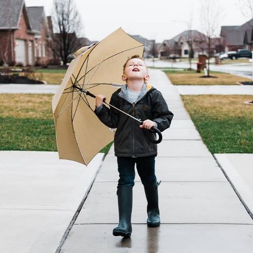 young boy with an umbrella catching raindrops
