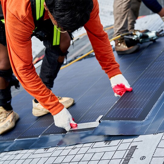 Roofing contractor installing solar roof shingles by GAF Energy
