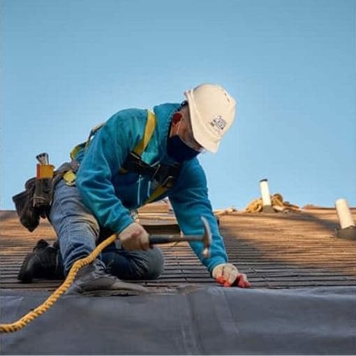 Roofing contractor on roof with hammer and nail