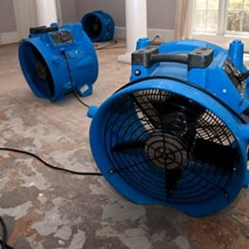 Large blue fans drying out areas of a home after a hurricane.