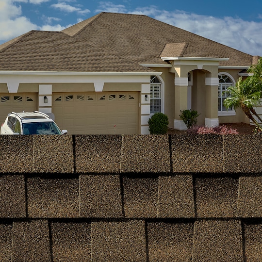 GAF Timberline HDZ® Barkwood Shingle closeup with sample product image on a taupe house.