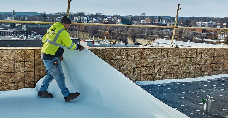 Capeway Roofing Systems, Inc. , a GAF Factory-Certified Contractor laying out GAF EverGuard SA TPO at the edge of the roof