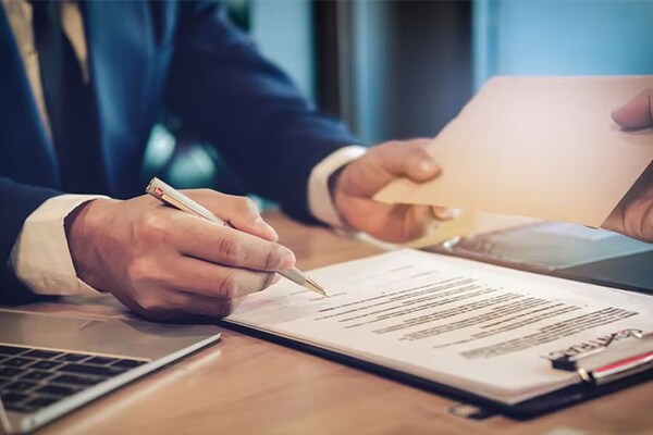 A person holding a pen to a document on a clipboard