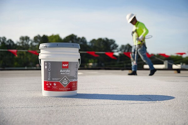A contractor applying GAF acrylic top coat on a flat roof.