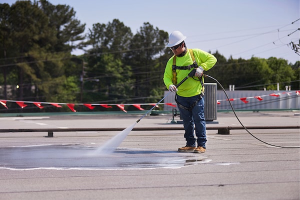 A contractor power washing a flat roof using GAf's Cleaning Concentrate