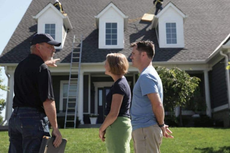 homeowners talking to contractor outside of their home