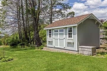 Light gray shed with brown GAF shingle roof.