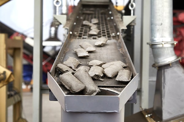 Asphalt shingle briquettes move along a conveyor belt as part of the GAF shingle recycling process.