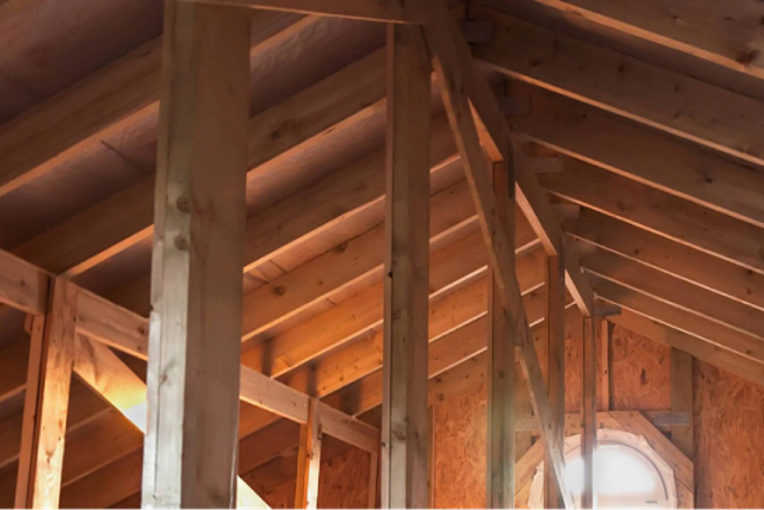 Exposed wooden rafters inside an attic