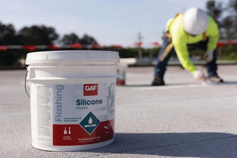 A contractor on roof applying GAF Silicone Mastic