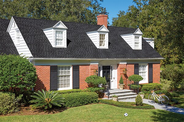 A house with a dark grey roof built with GAF asphalt shingles made from reclaimed materials. 