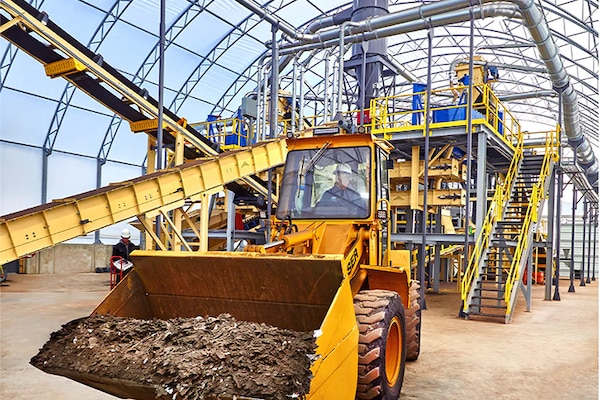 A tractor vehicle moves raw material through a GAF shingle recycling facility.