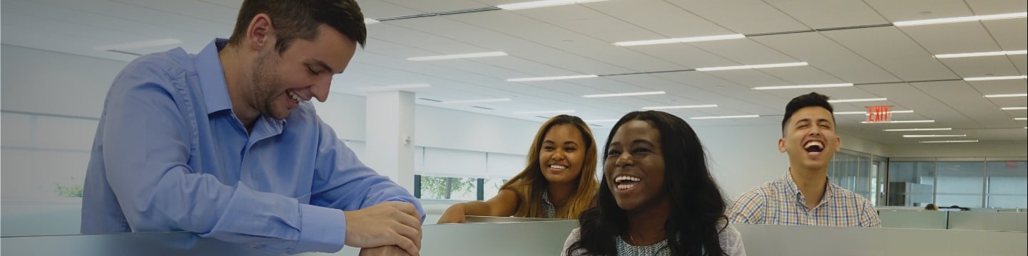 Four young GAF employees laughing and smiling in office setting