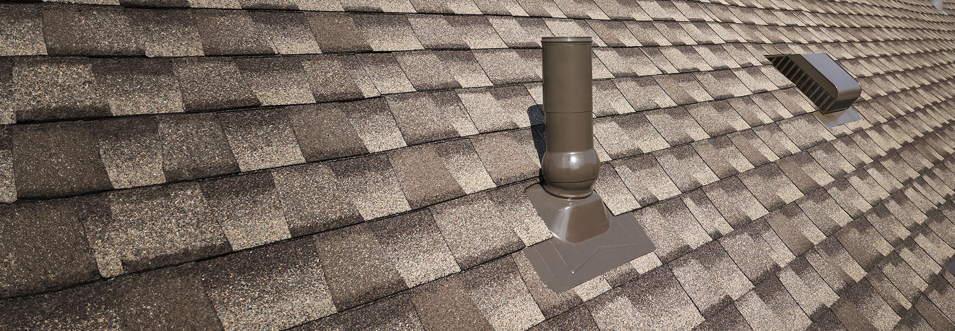 A close-up view of an asphalt shingle roof featuring GAF roof accessories that can help reduce water penetration. 