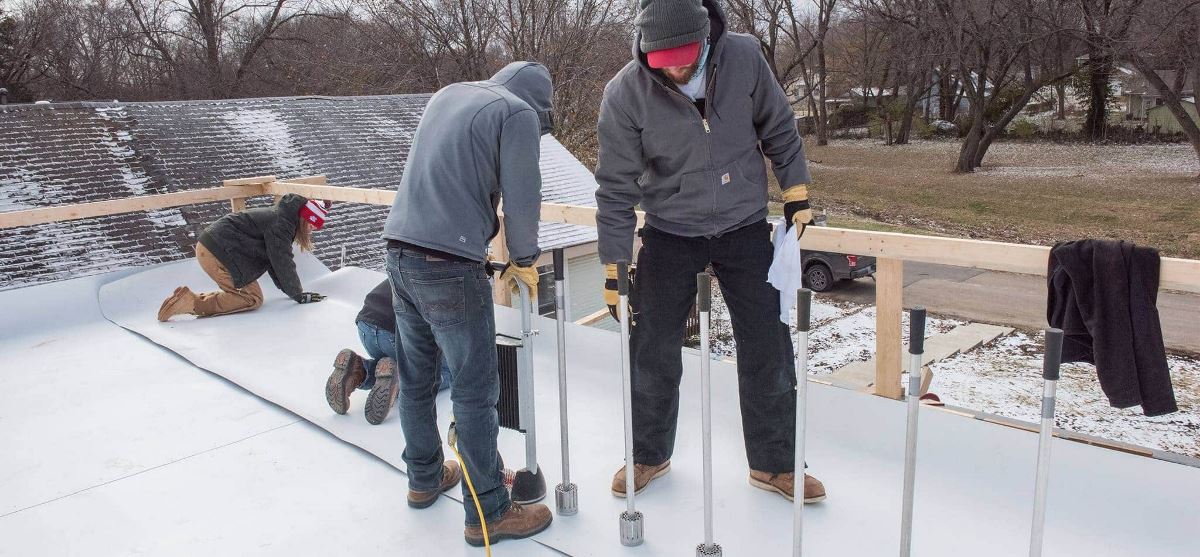 University of Kansas graduate students on a flat roof installing GAF commercial roofing materials