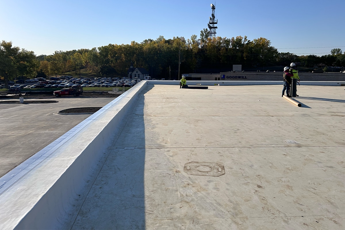 Roofing contractors rolling out TPO membranes on the roof of the Goodwill of the Great Plains headquarters