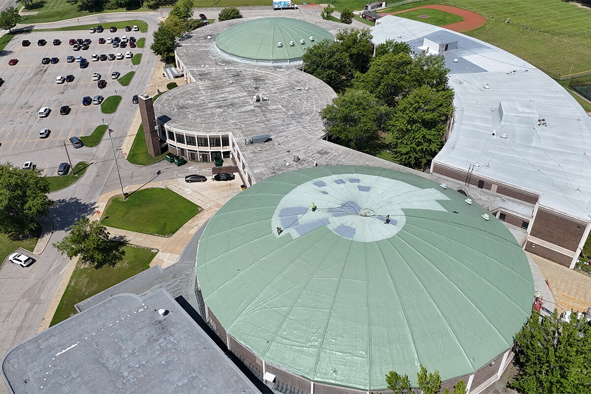 Aerial view of completed GAF silicone roof restoration showing Patina Green domes and white classroom wing at Normandy High School in Parma, Ohio