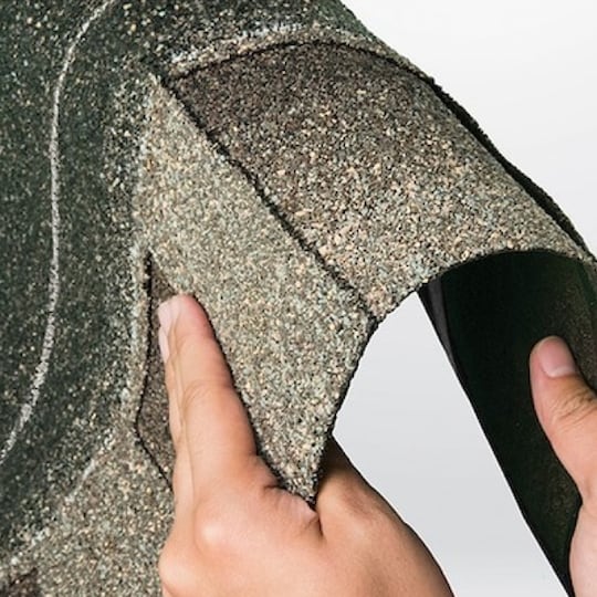 Hands bending a strip of Timberline ArmorShield II shingles, showing how flexible and durable it is.
