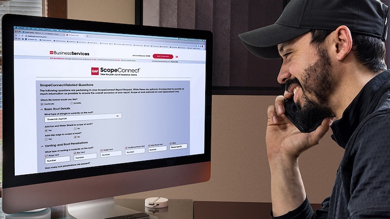 Roofer on phone viewing GAF ScopeConnect on computer