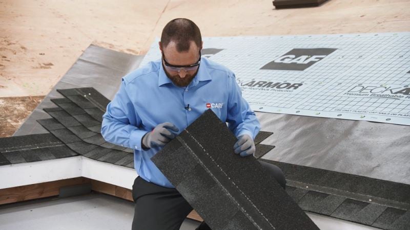 Man holding GAF roofing shingle with roofing nail accuracy from widest nail zone
