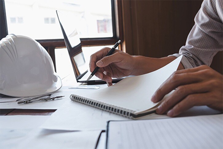 Person using paper and pen to finalize GAF Seam Tape application instructions.


