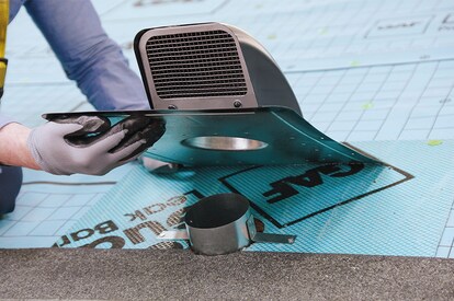 A contractor inserting the vent’s neck into a circular opening in the roof deck