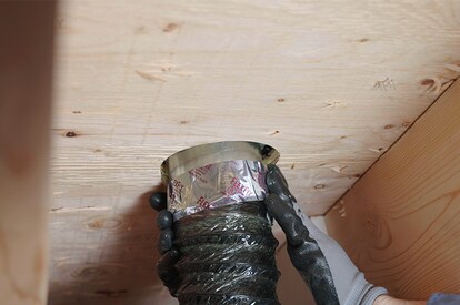 Underneath view of a contractor using the included removable duct collar to hook the vent up to ducts