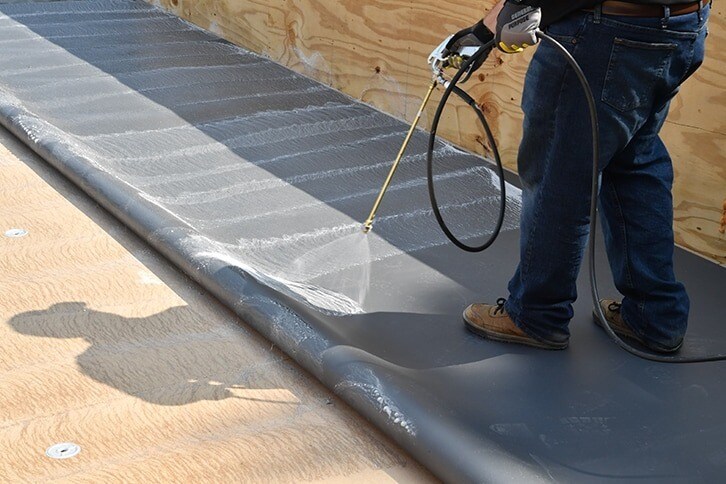 Contractor spraying EverGuard TPO Quick Spray Adhesive to save application time