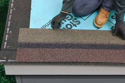 Roofer positioning and cutting StarterMatch starter strip shingles over roof underlayment.