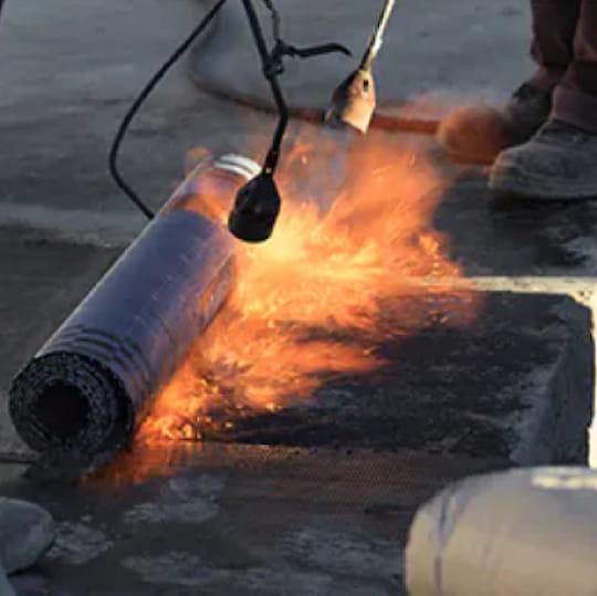 Contractor applying Mod Bit APP roofing system