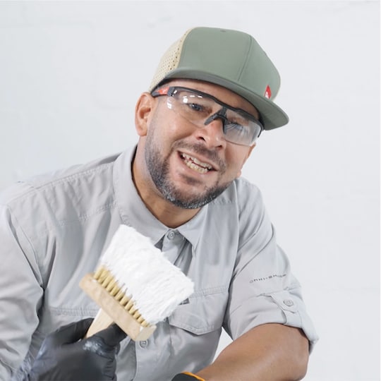 GAF worker holding a brush, demonstrating how to apply GAF  coatings products. 