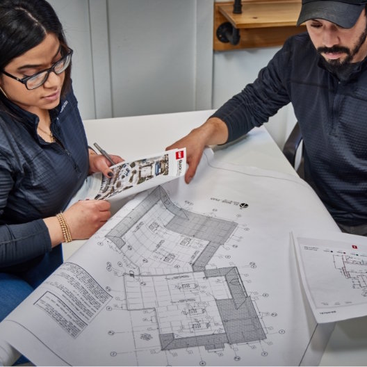 Man and woman reviewing GAF QuickMeasure aerial roof reports 