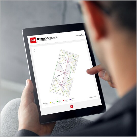 GAF certified contractor using GAF QuickMeasure, roof measurement tool, on a tablet.