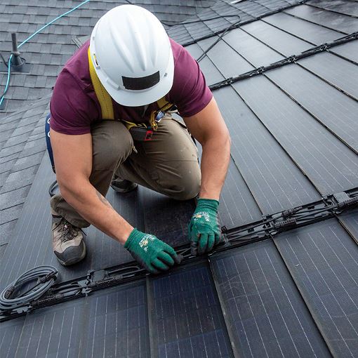 Roofing contractor installing solar roof shingles