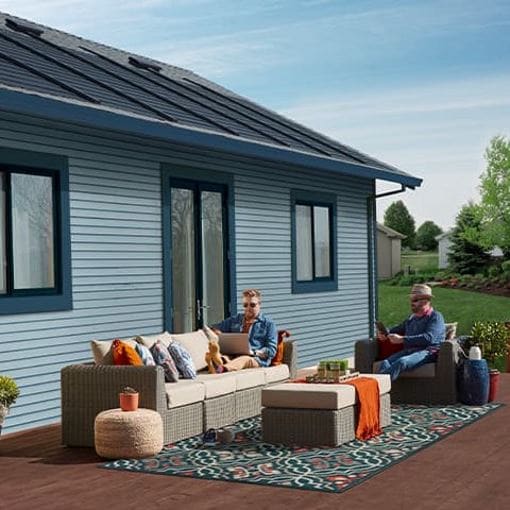 Homeowners sitting on deck furniture outside home with solar roof