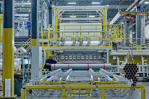 Factory worker using a machine to roll TPO roofing rolls