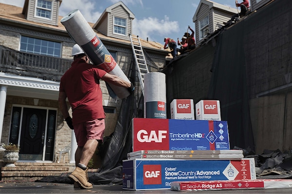 Packages of impact-resistant roofing materials manufactured by GAF stacked together at a home construction site.