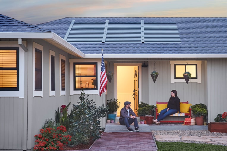 Man and woman on porch sitting oustide home with solar roof