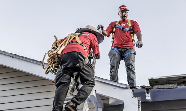 Volunteers wearing red t-shirts with The “Community Matters” logo on them work on a rooftop. 